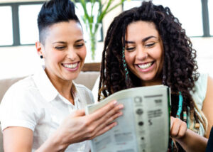 Two women smiling and reading a paper