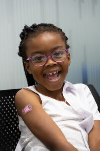 Black girl smiling with plaster on arm from vaccination