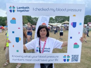 Vanita at the Lambeth Country Show. She's holding a frame around her which says 'I checked my blood pressure'.