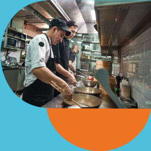 Two male chefs cooking on a hob in a professional kitchen