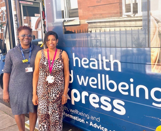 two pharmacists stand in front of Blue Health and Wellbeing Bus in Brixton