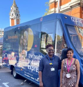 two phramcists stand in fron to Lambeth health and wellbeing bus in Brixton town centre