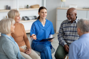 Patients sitting in a circle talking with a doctor who is taking notes.