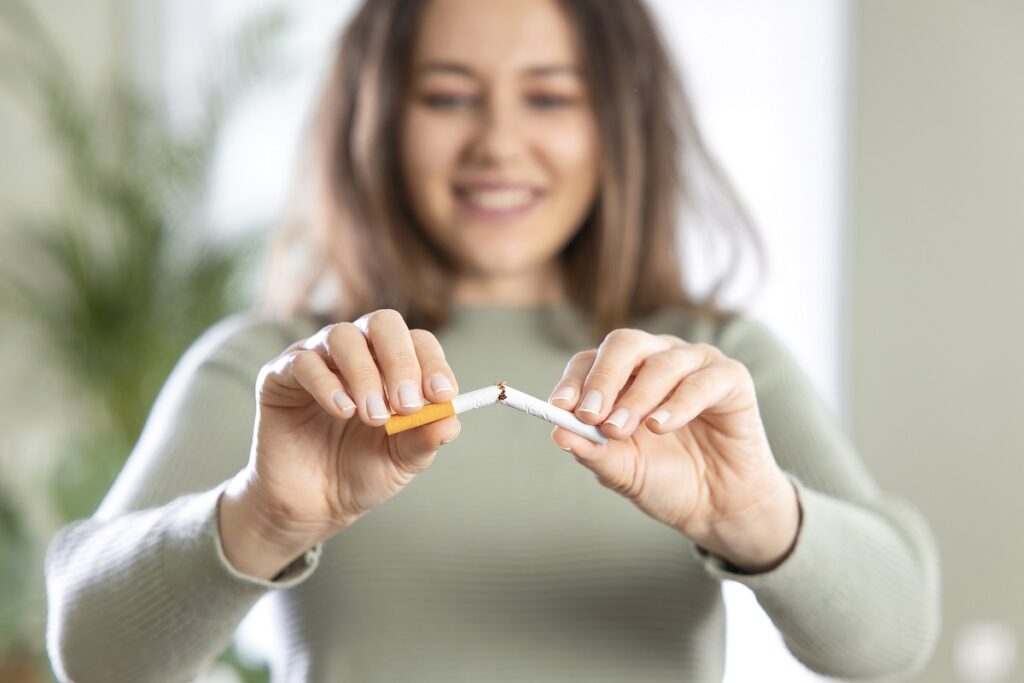 Young woman breaking cigarette. Stop smoking cigarettes concept