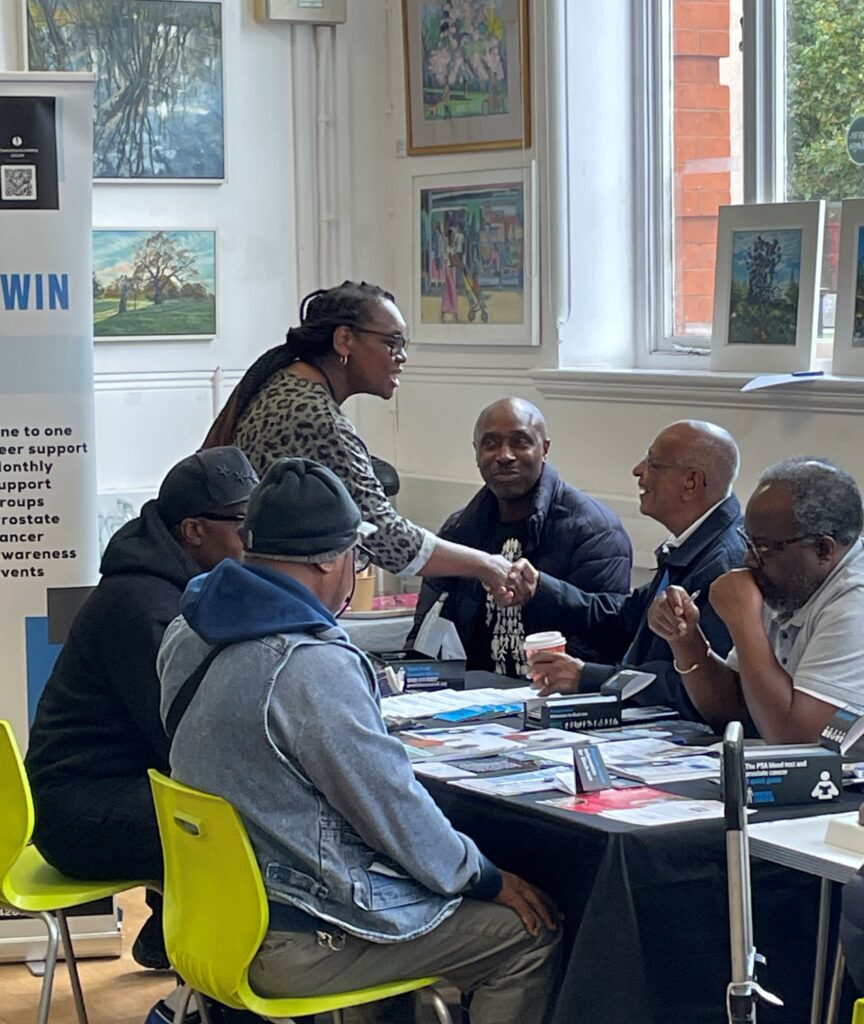 people attending cancer awareness event at library are sitting down at a table and talking to cancer experts about prevention and NHS screening programmes