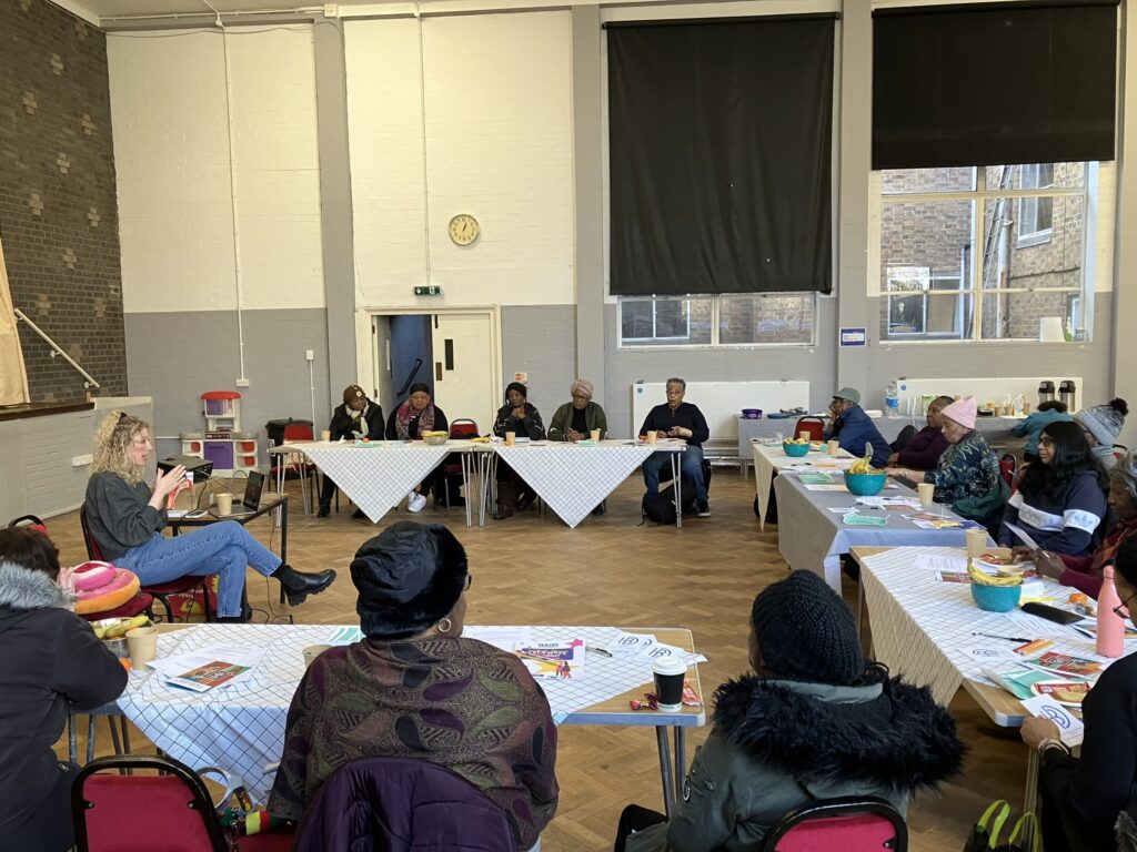 Attendees sit around a table whilst a speaker is talking 