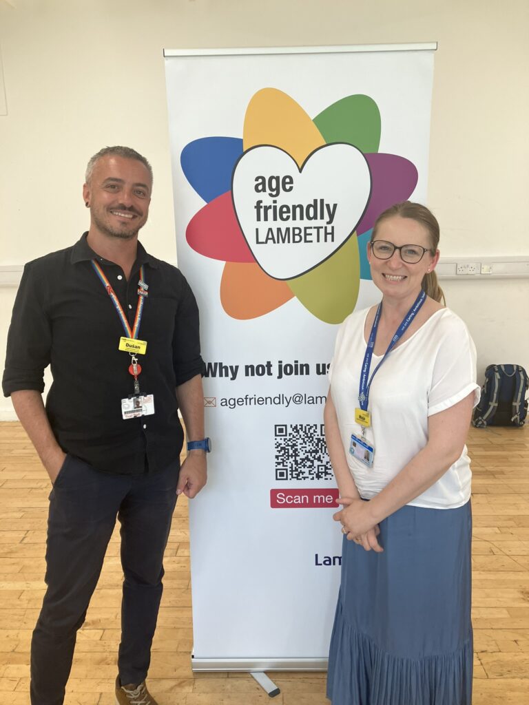 Dušan (Bowel Cancer Lead) and Maja (Ageing Well Practitioner) stand with the age friendly Lambeth standing sign. 