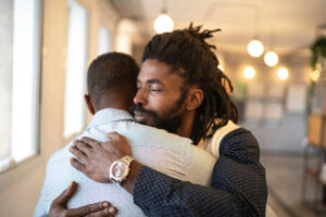 One black man hugs another with empathy