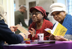 two older black women getting information at a health stall. one holds a leaflet on glaucoma