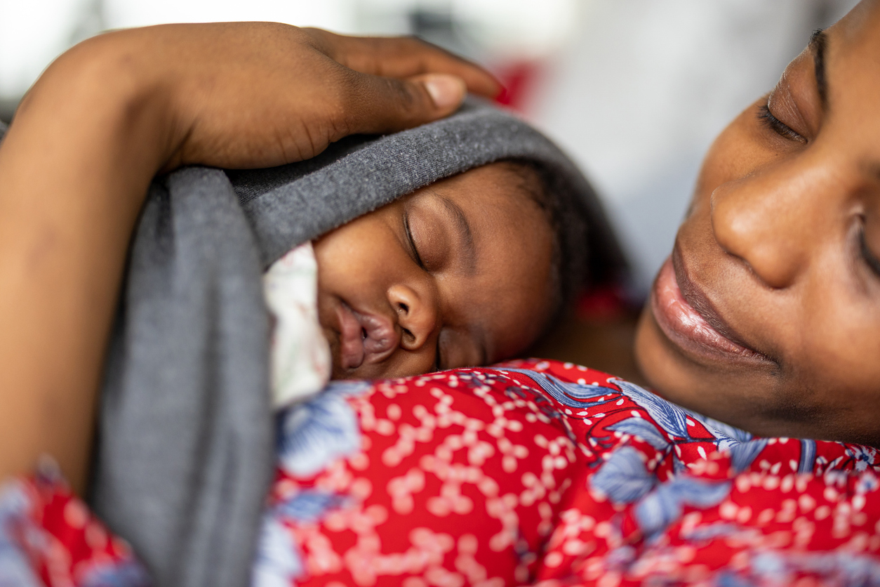 Mother cuddling her sleeping baby at home
