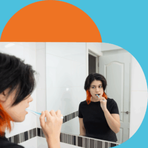  Person with short dark hair and orange streaks brushing teeth in front of a bathroom mirror