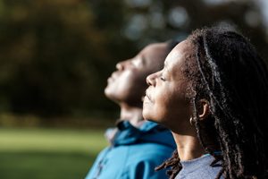 Two people with their heads tilted back and eyes closed, enjoying the sun.